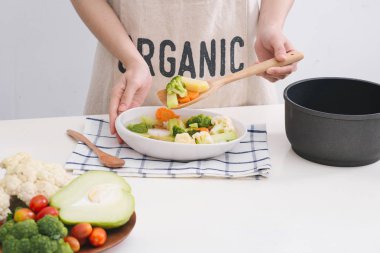 Kadın heyecan sebze pan ve tatma yemek mutfakta. 