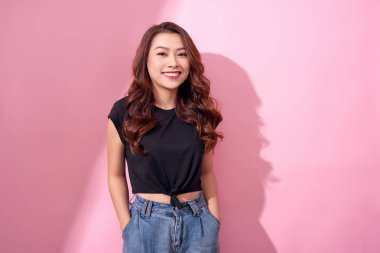güzel portre Asyalı neşeli genç kız pembe arka plan izole gülümseme ayakta gülen ile rahat giysiler içinde poz 