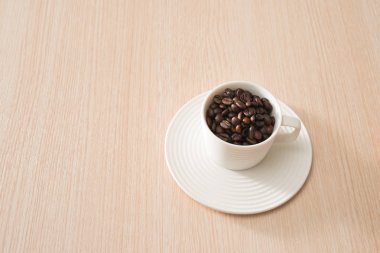 Ahşap arka plan üzerinde tam kahve çekirdekleri Fincan