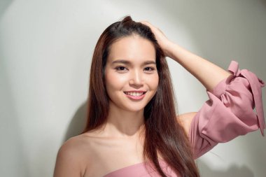 Beton duvara poz veren genç bir kız, pembe ve sert giyinmiş.