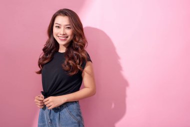 güzel portre Asyalı neşeli genç kız pembe arka plan izole gülümseme ayakta gülen ile rahat giysiler içinde poz 
