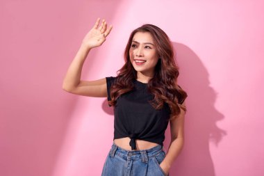 Genç ve güzel Asyalı kadın pembe arka planda izole edilmiş güneş ışığından korkuyor. Yazın cilt bakımı ve güneş ışığından korunma kavramı 