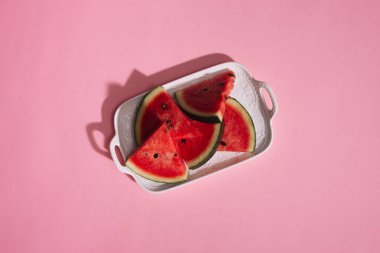 Pembe bir arka plan üzerinde beyaz tabak taze dilimlenmiş karpuz.
