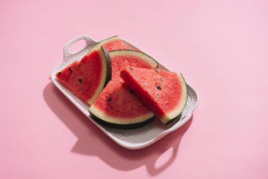 Pembe bir arka plan üzerinde beyaz tabak taze dilimlenmiş karpuz.