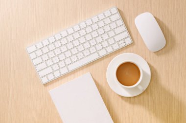 Düz yatıyordu, en iyi görünümü office tablo Resepsiyon. Çalışma alanı boş not defteri, klavye, ofis malzemeleri ve ahşap zemin üzerine kahve fincanı.