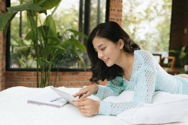 Kalem ve defteriyle yatak odasında yazan mutlu genç bir kadın. 