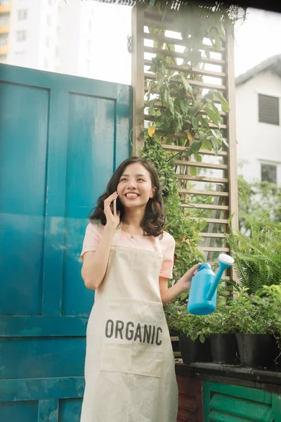 Tukang Kebun Perempuan Menggunakan Ponsel Saat Menyiram Kebunnya — Stok Foto