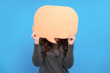 Sarı baloncuk tutan genç ve güzel bir kız, mavi arka planda izole edilmiş.