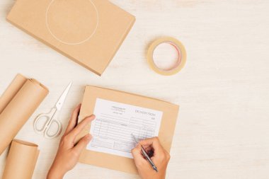 Masadaki karton kutuya yazı yazan kurye elleri. 