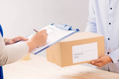 Kadın müşteri makbuzu imzaladı ve teslimatçıdan paketi aldı. İş ve lojistik kavram.