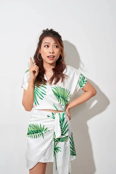 Cute asian woman in tropical print green dress thinking and imagination on white background