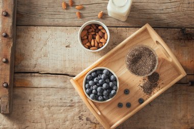 Taze yaban mersini, badem ve chia tohum ahşap tahta üzerinde süt ile. İdeal sağlıklı kahvaltı konsepti. 