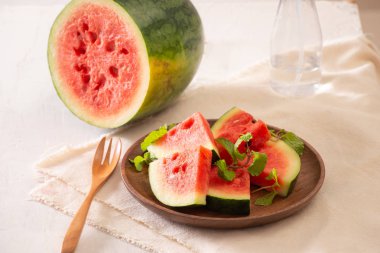 Arka planda ahşap bir plaka üzerinde dilimlenmiş tatlı karpuz