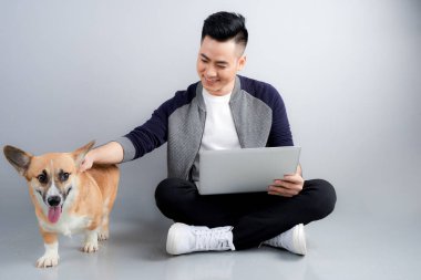 Yakışıklı genç işadamı köpeğiyle katta otururken dizüstü kullanıyor