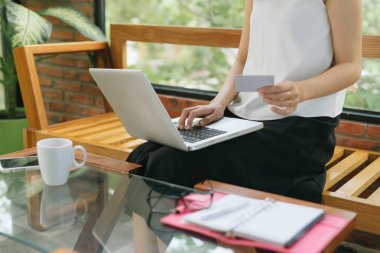 Kredi kartı tutan ve dizüstü bilgisayar kullanan bir kızın portresi. İnternetten alışveriş