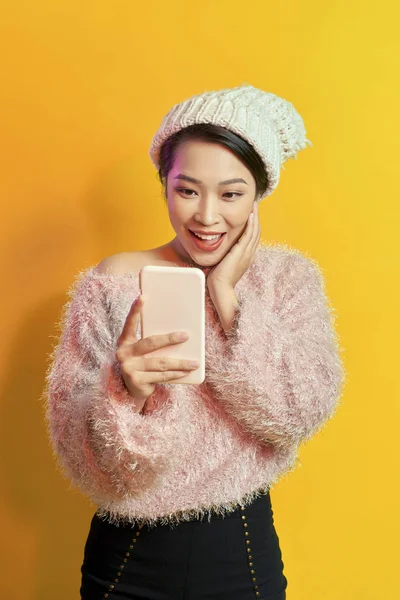 兴奋的短发女人拿着智能手机在橙色的背景 室内照片的精彩女模特与手机摆姿势 — 图库照片