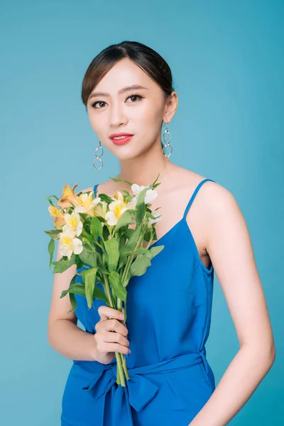 Atractiva mujer asiática en vestido azul sosteniendo ramo de flores — Foto de Stock
