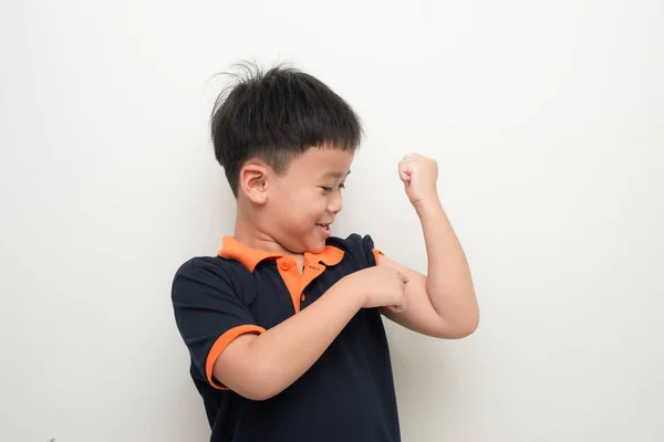 彼が強いと言うために彼の二頭筋を指差す若いアジアの少年 — ストック写真