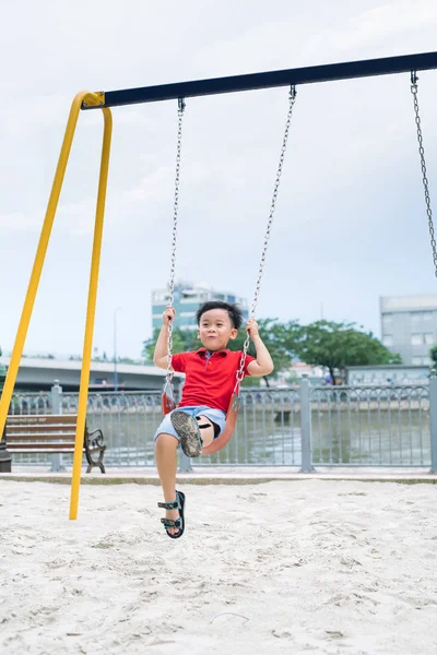 Szczęśliwy Chłopiec Azjatyckich Kołysząc Się Placu Zabaw Parku — Zdjęcie stockowe