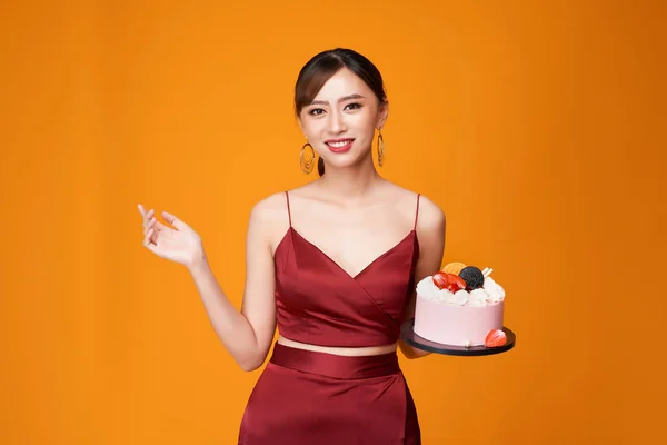 誕生日ケーキを運んでいる赤いドレスのエレガントな女性の垂直ショット — ストック写真