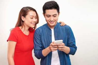 Asyalı çift kullanarak cep akıllı telefon mesajı gülümseme beyaz arka plan üzerinde ayakta