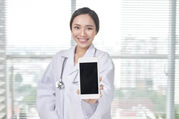 Female doctor shows blank screen of smartphone.