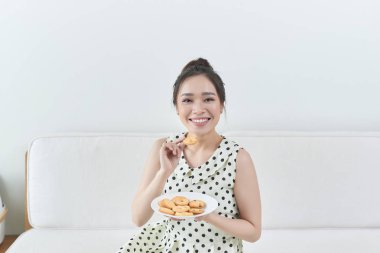 Mutlu kız evde bir kanepede oturan bir diyet çerez yemek