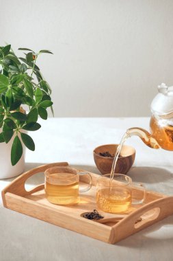 Ahşap servis tepsisinde cam Çaydanlık bir el çay dökme