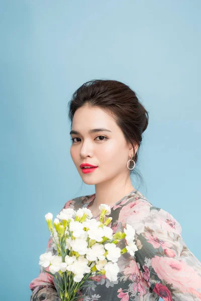 Portrait of tender asia woman with bouquet  on blue background