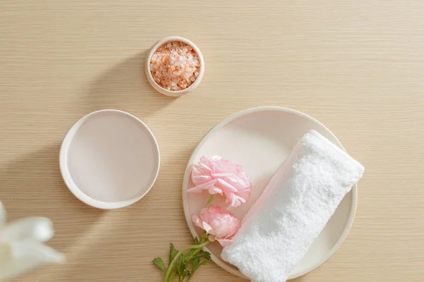 Spa setting of salt, towel, flower on plate on wood background with copy space. Relax. Close up. Top view.