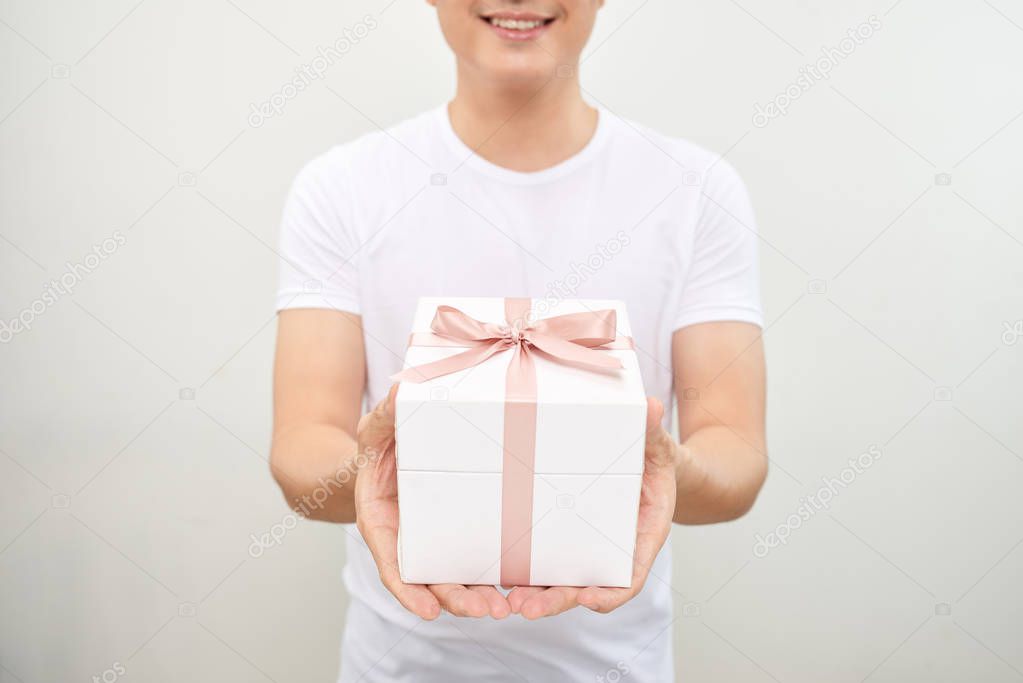 A happy handsome man presenting some gifts. Isolated on white background.