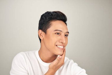 Mutlu genç Asyalı adam yanağına dokunuyor