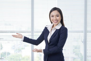 Gülümseyen genç kadın bir şey gösteriyor.