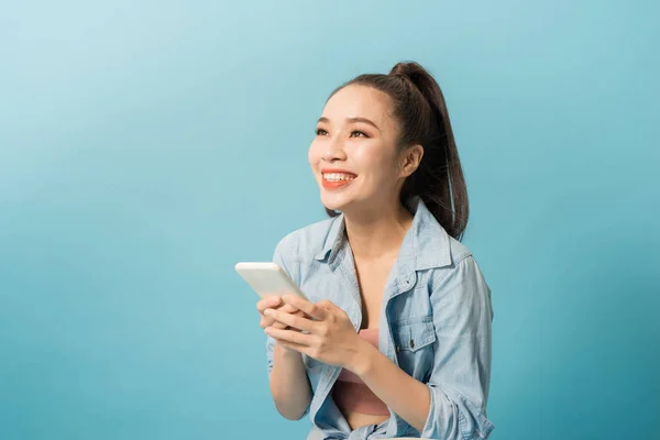 Asijská Žena Držící Mobilní Telefon Usmívající Přes Modré Pozadí — Stock fotografie