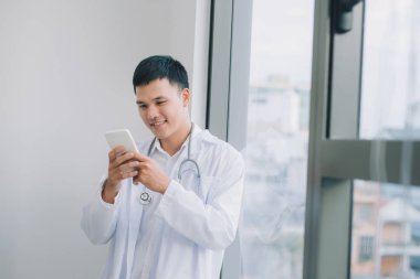 mutlu genç doktor cep telefonu tutarak