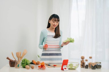 Mutlu kadın tarifi mutfakta tablet bakarak önlük. Sebze salatası. Diyet kavramı. Sağlıklı bir yaşam tarzı. Evde yemek. Yemek hazırlamak.