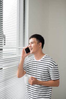 Bir cep telefonu üzerinde kopya alanı içeren bir pencere, sabah konuşurken rahat kıyafetler giyen genç adam,