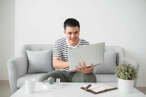 Jovem Atraente Usando Laptop Enquanto Deitado Sofá Com Expressão Feliz — Fotografia de Stock