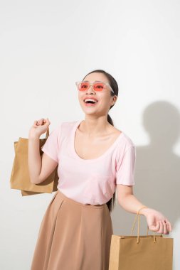 Alışveriş torbaları tutan genç kadın gülümseyerek ve üzerinde beyaz izole kamera gülümseyen
