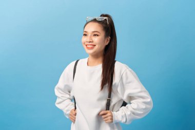 Asya öğrenci kız üzerinde izole mavi duvar mutlu ve gülümseyen