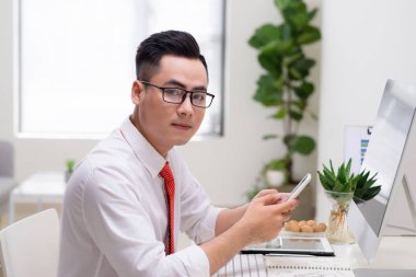 Ofiste cama tabloda, bilgisayar ve akıllı telefon kullanan adam