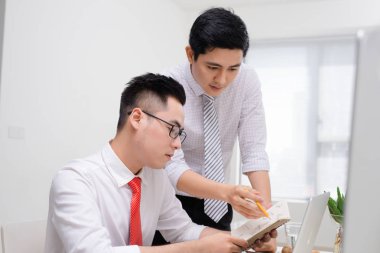 Ofis masası bilgisayar ile birlikte çalışma iki iş adamları, onlardan biri ekranında işaret.