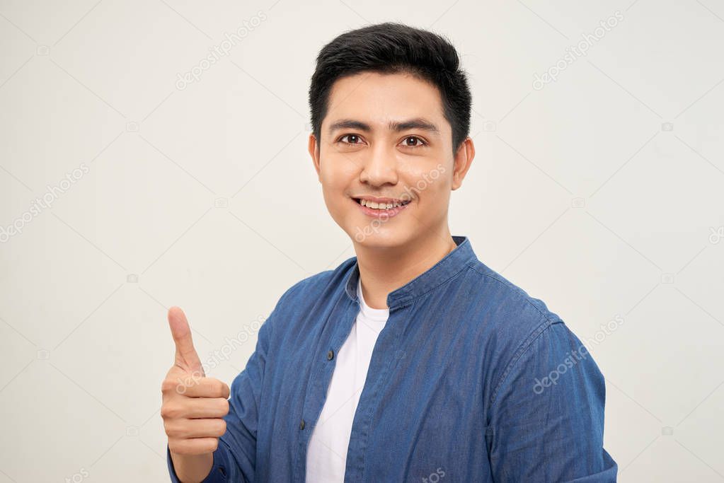 An attractive man with a big smile on his face, doing a thumbs up against a camera