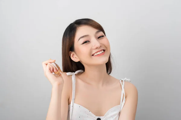 白い背景に香水を使用して笑顔の魅力的な若いアジアの女性の肖像画 — ストック写真