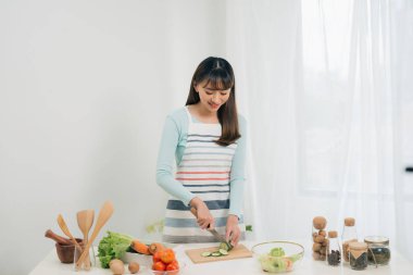Genç kadın mutfakta sebze kesiyor. Kadın sağlıklı gıda pişirme. 
