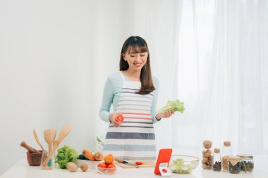 Mutlu kadın tarifi mutfakta tablet bakarak önlük. Sebze salatası. Diyet kavramı. Sağlıklı bir yaşam tarzı. Evde yemek. Yemek hazırlamak.