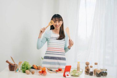 Güzel genç asyalı kadın yemek tarifi okuma veya salata yaparken göstermek izlerken