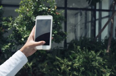 Fotoğraf çekmek veya dışarıda mesaj atmak için akıllı telefonu kullanan kadın