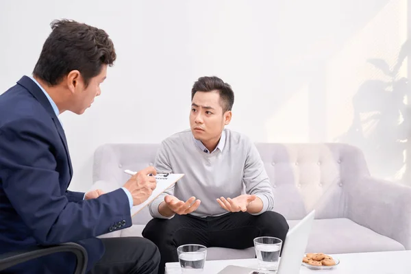 Listen to me. Asian man wrinkling forehead while looking at his therapist
