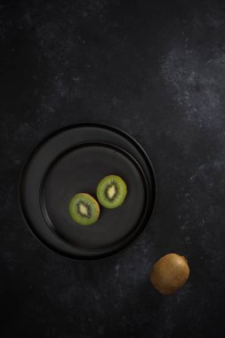 Siyah tabakta yeşil kivi nin iki yarısı. Taze olgun meyve. Sağlıklı gıda kavramı.